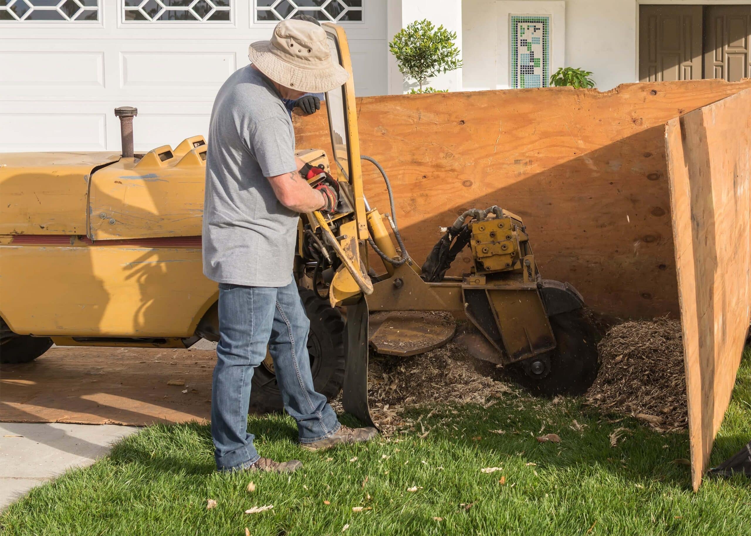 Worker using a machine to perform a stump grinding service.